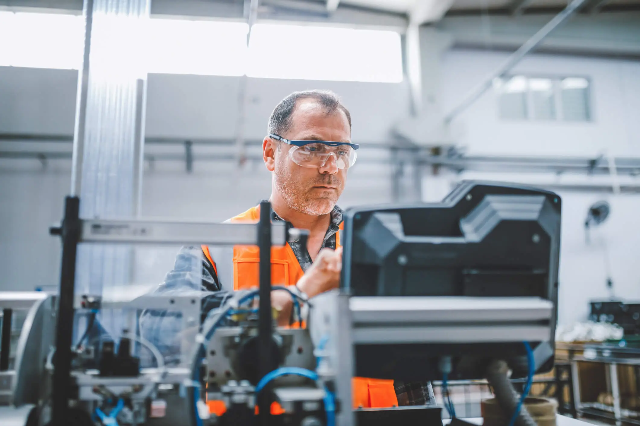 Un employé d’usine industriel professionnel travaillant avec des pièces de machine mettant, vérifiant et testant des câbles d’équipement industriel dans un grand entrepôt d’usine de fabrication de fils et de câbles électroniques électriques